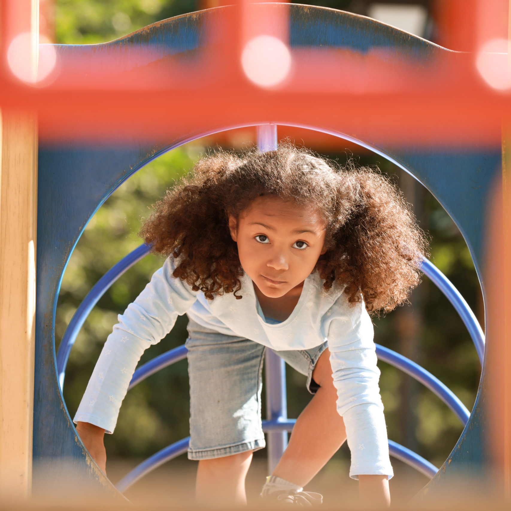 Cute African-American girl having fun on playground outdoors